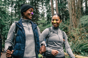 Happy, smiling mother and daughter hiking outdoors wearing colorful reef safe zinc oxide sunscreen on their noses